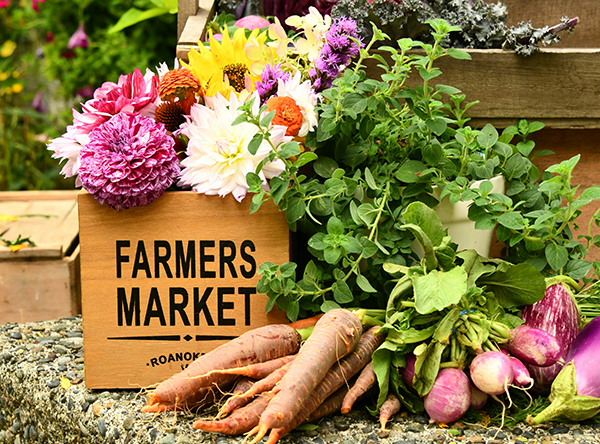 A box with "Farmers Market" written on it, surrounded by flowers and vegetables