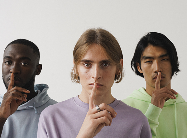 Three people hold their finger in front of their mouths