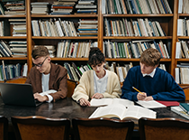 Three people studying in a library