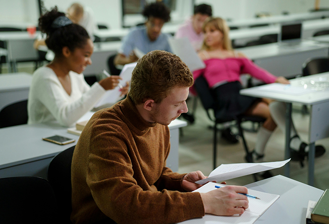 A student writes while sitting at a desk