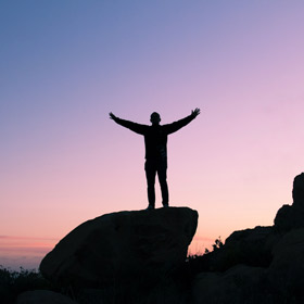 person standing on boulder with arms raised
