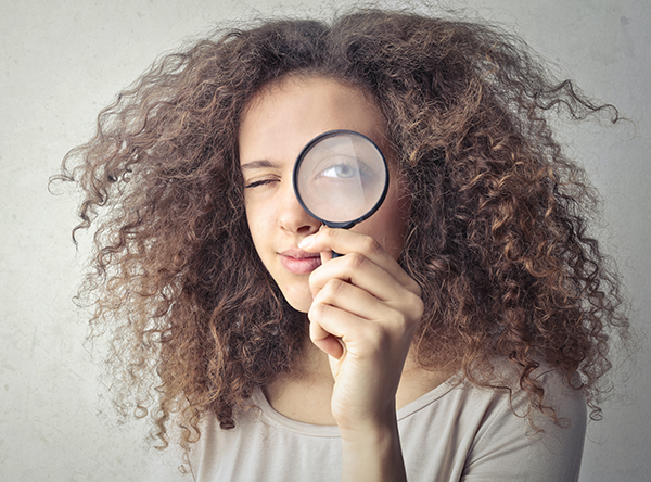 A person holds up a magnifying glass