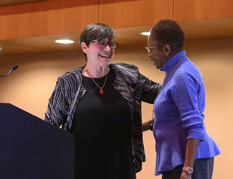 Two people greet one another on a stage