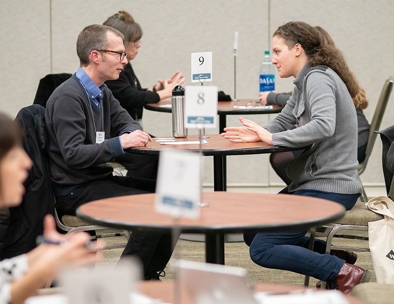 Two people sit across from each other at a table